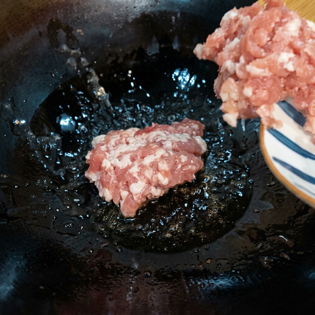 Minced meat being stir-fried in a hot wok over medium-low heat until browned.