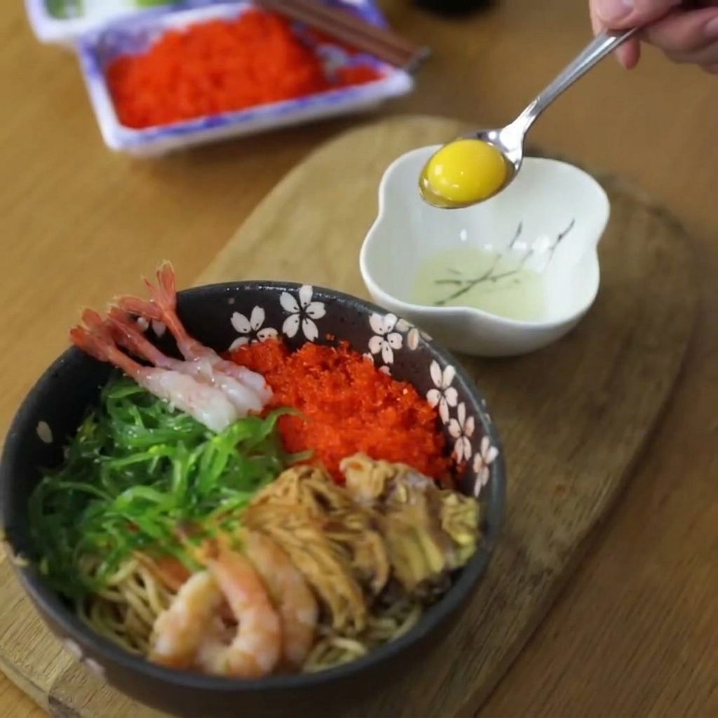 A raw, vibrant yellow quail egg yolk being lifted with a small metal spoon from a white bowl.