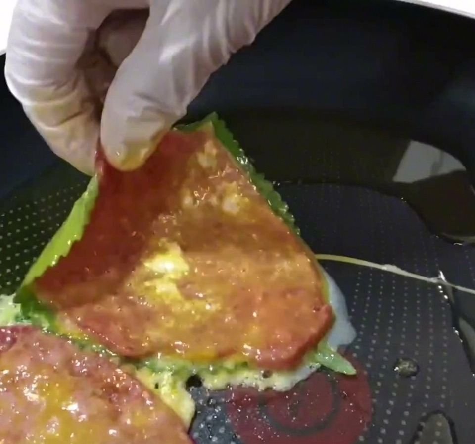A beef and perilla leaf pancake being placed into a preheated frying pan with oil.