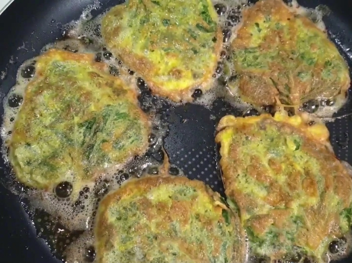 A cooked perilla beef pancake being lifted out of the pan with a spatula and chopsticks.