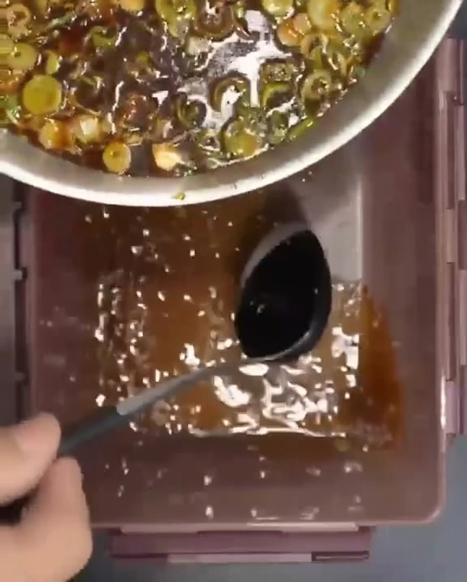 Raw beef ribs arranged in a container with the flavorful marinade being poured over them.