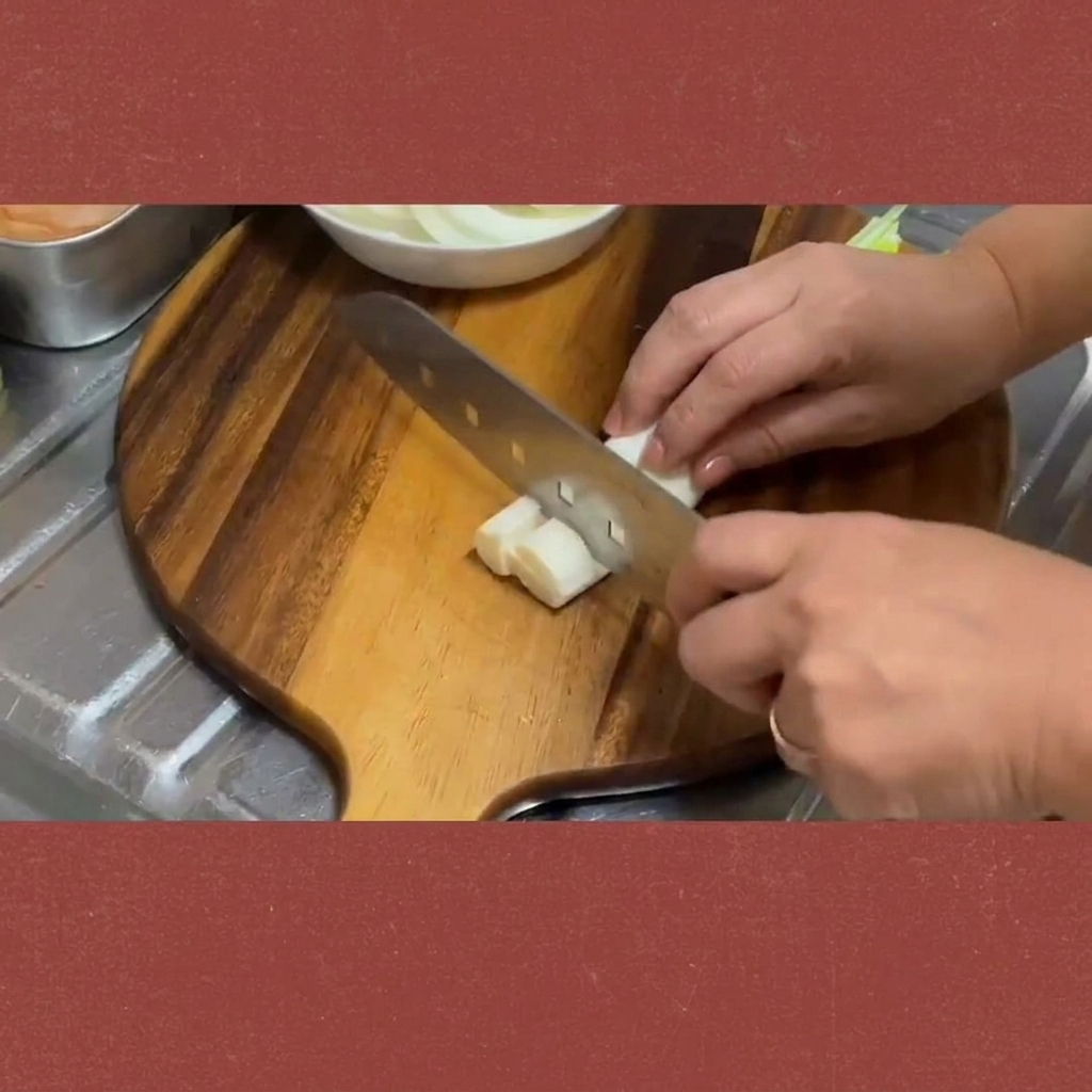 Fresh green onion stalks being cut into uniform segments on a cutting board.