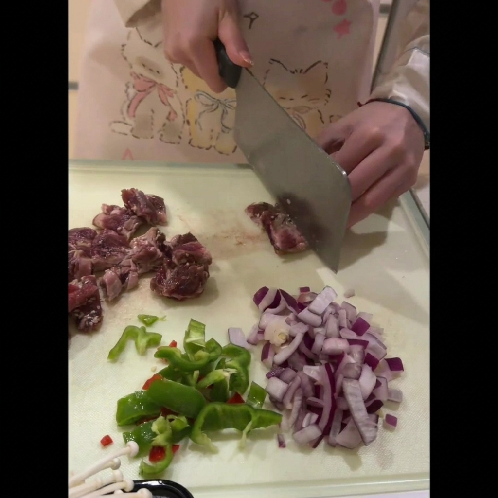 Fresh beef ribs being carefully sliced into uniform, bite-sized pieces on a cutting board.