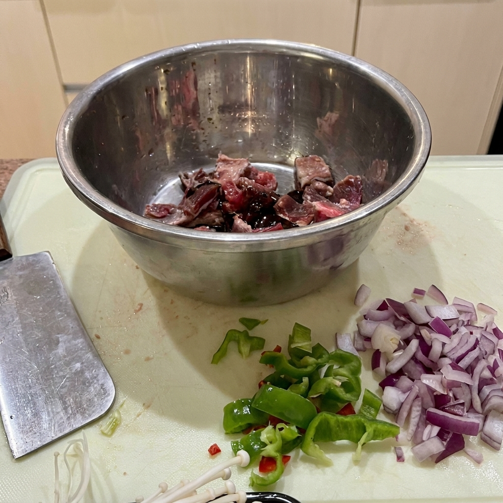 Beef pieces marinating in a stainless steel bowl with soy sauce, oyster sauce, and starch.