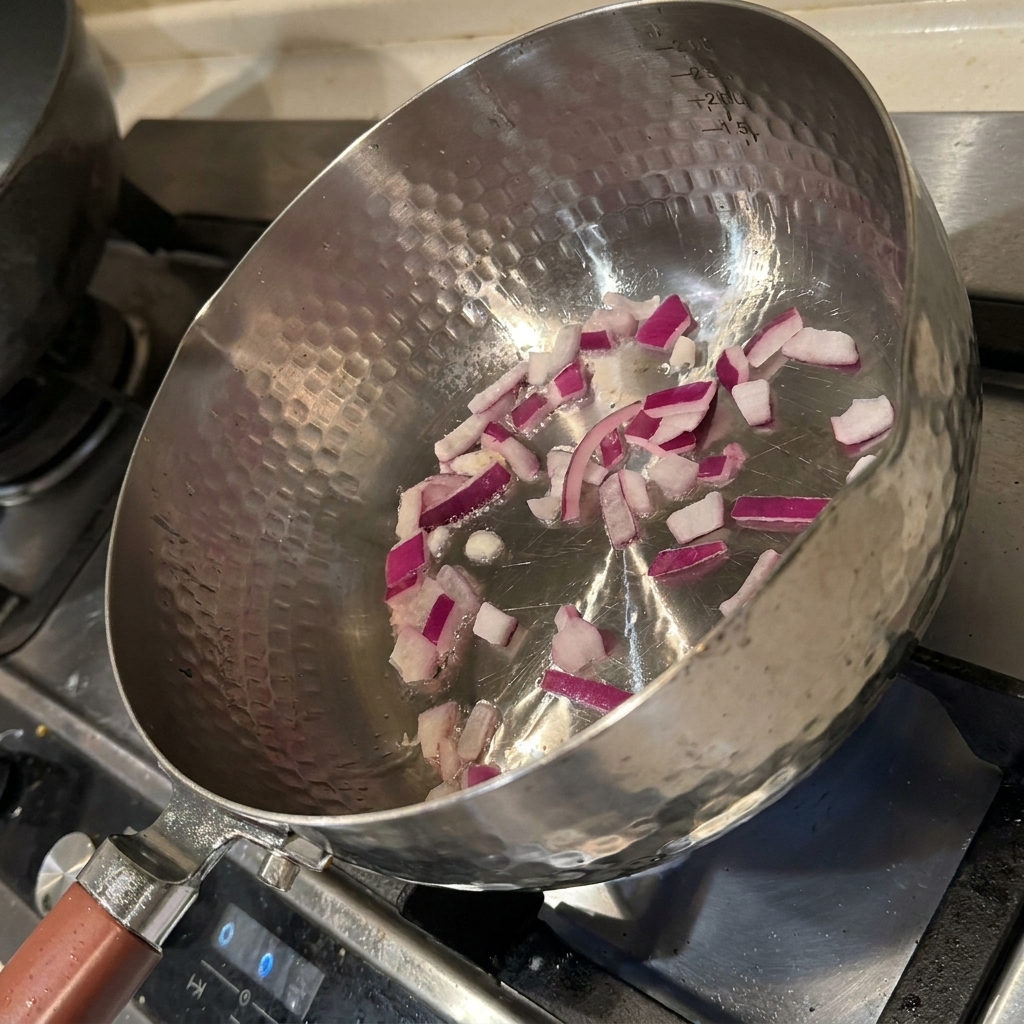 Onion pieces sizzling in a hot pan with oil, turning fragrant and soft.