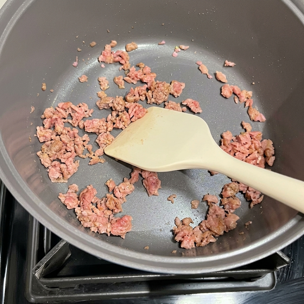 Kimchi and browned Spam being stir-fried together in a pot.