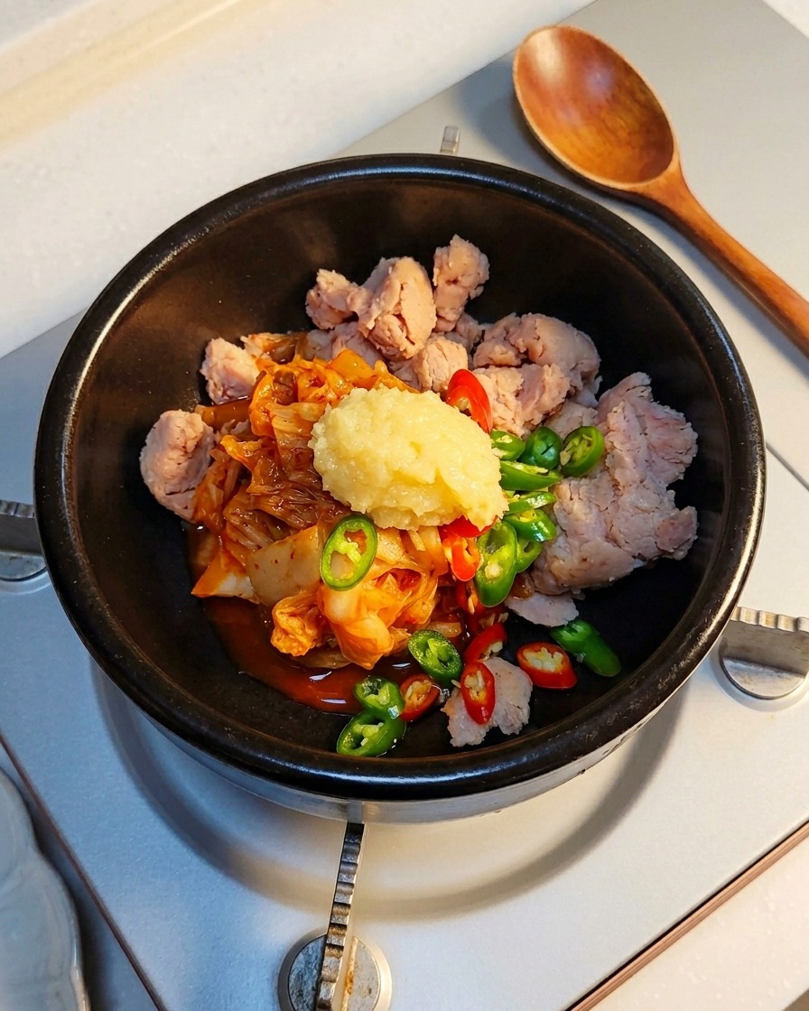 A spoonful of minced garlic being added to the stone pot ingredients.