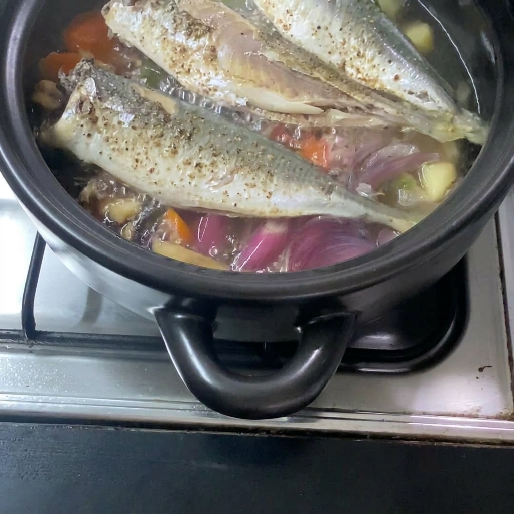 The liquid miso mixture being poured into the pot, integrating with the cooked mackerel and vegetables.