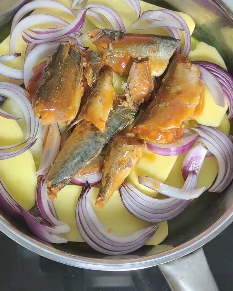 Tomato sauce from the mackerel can being poured into the pot with other ingredients.