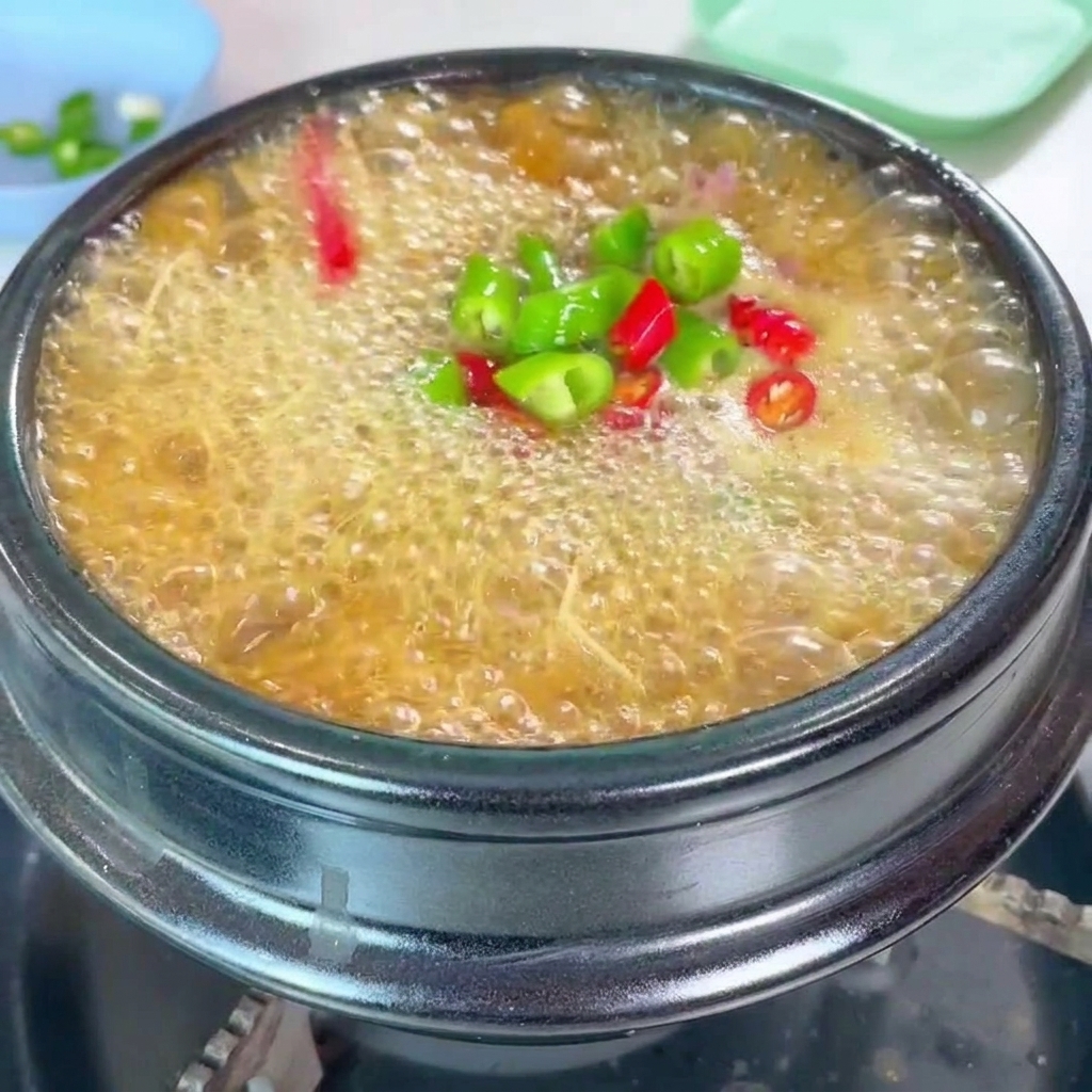 A vibrant topping of chopped green and red chili peppers and fresh scallions added to the simmering stew.