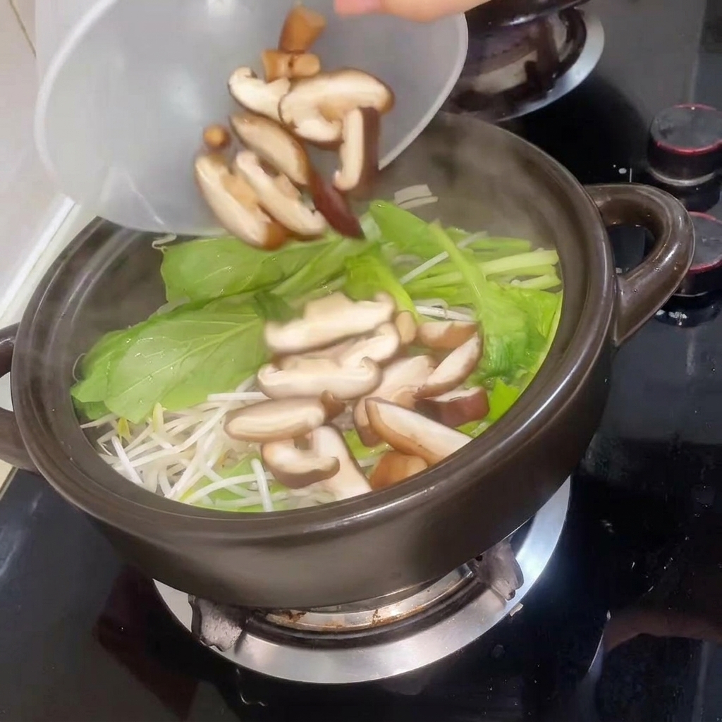 Sliced shiitake mushrooms being added to the pot followed by hot water.