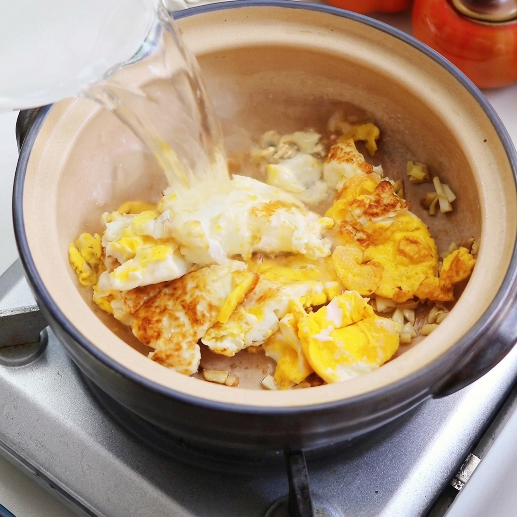 Water being poured into the clay pot over the fried eggs.