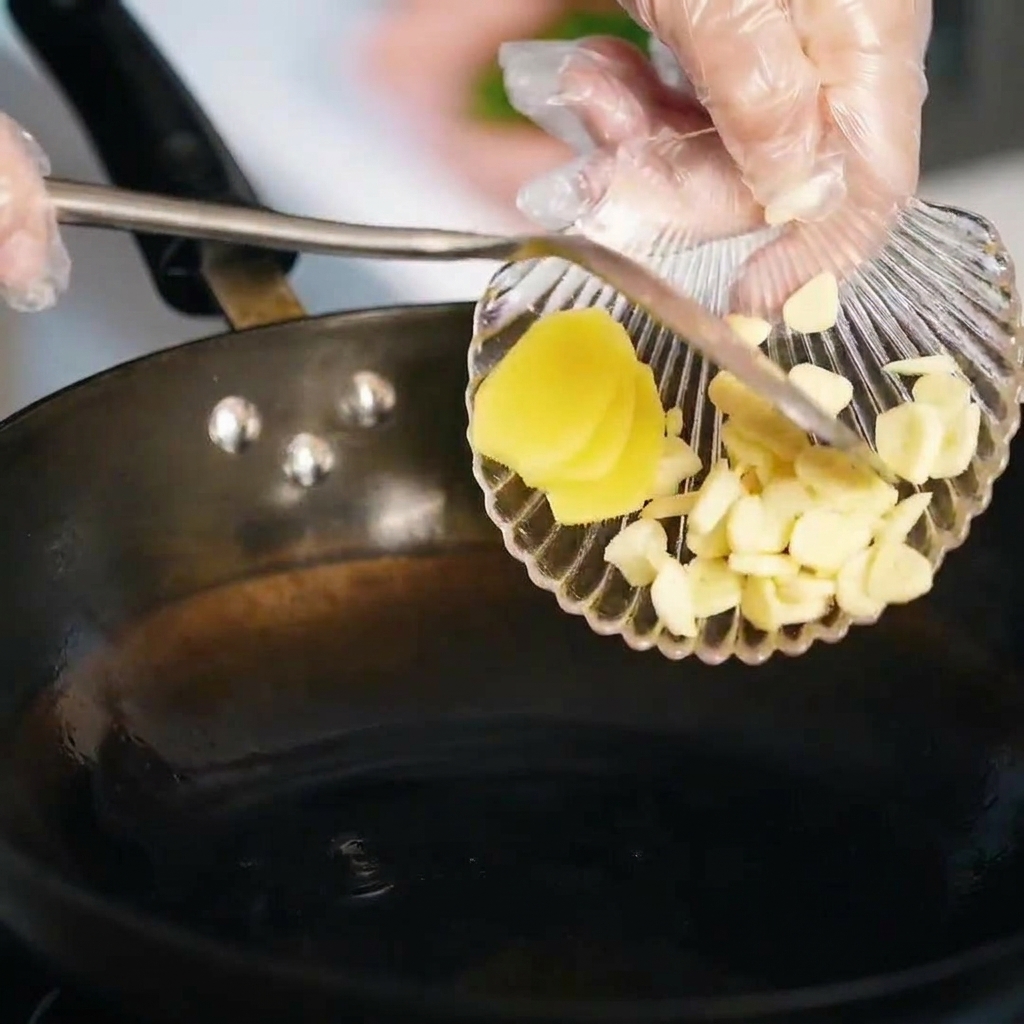 Sliced garlic and ginger being sautéed in melted lard.