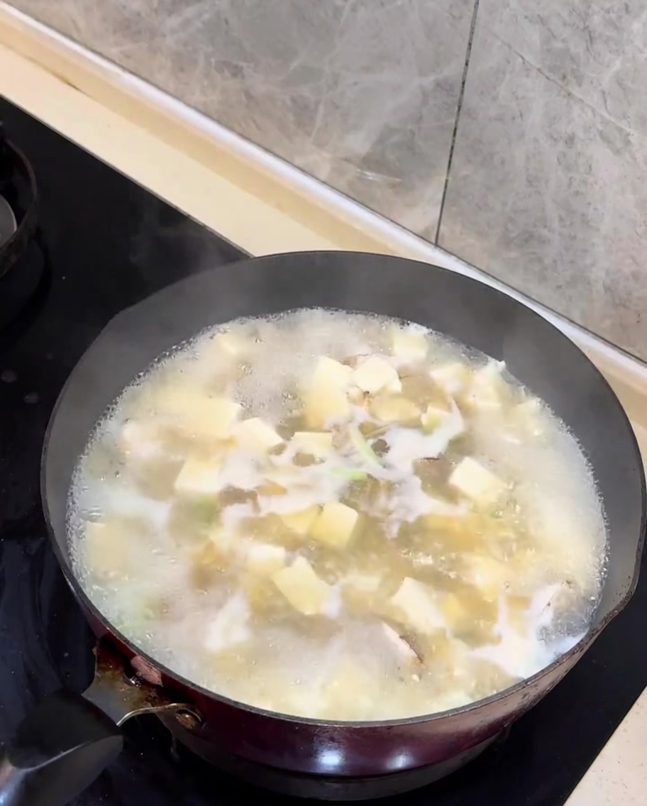 Chopped scallion greens being added to the finished clam and tofu soup.