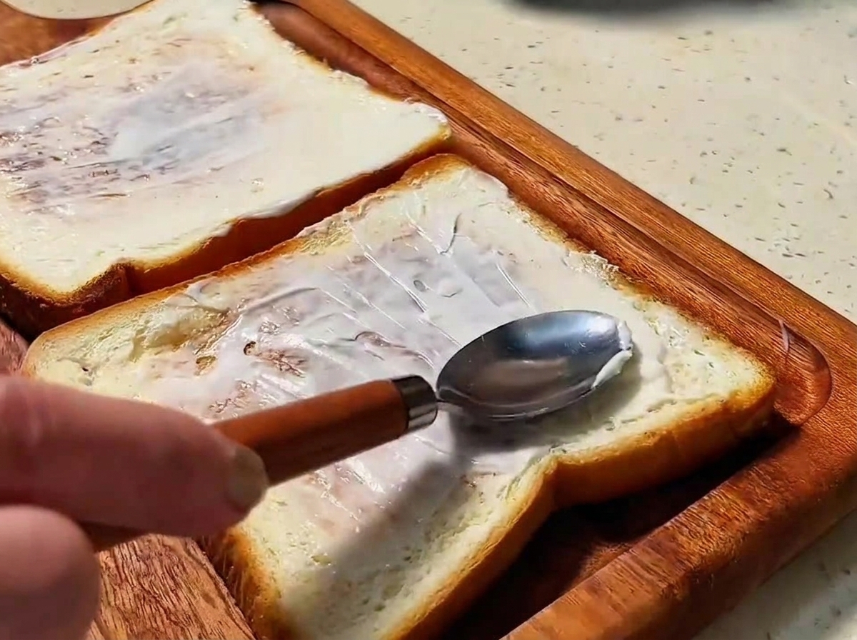 Two slices of golden-brown toasted bread spread with a smooth layer of mayonnaise.