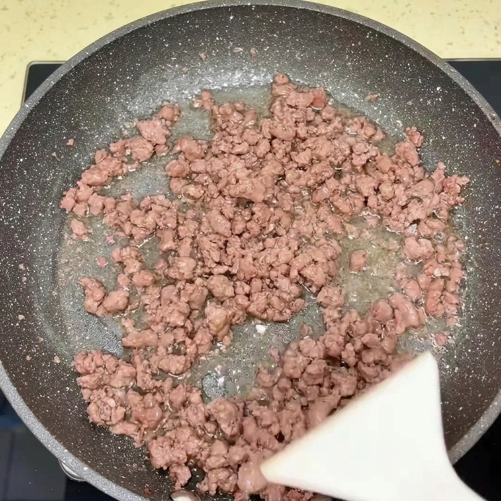 A pan containing cooked beef and onions