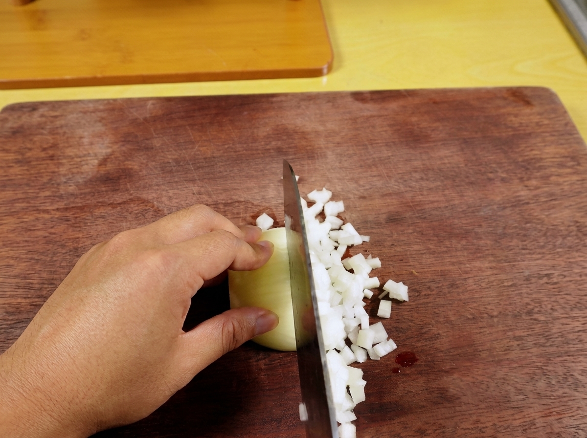 Fresh green chili being finely minced on a wooden cutting board.