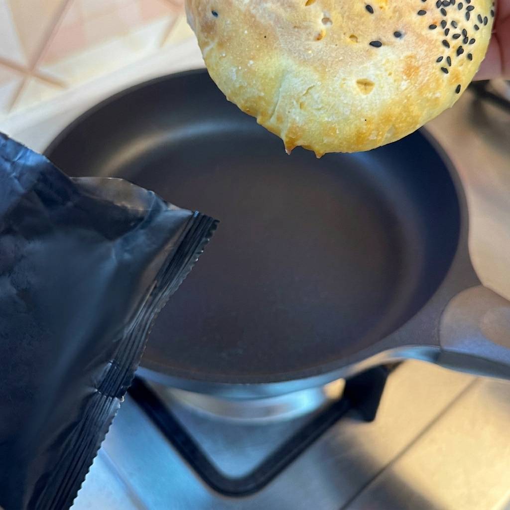Burger buns toasted to a golden brown in a frying pan.