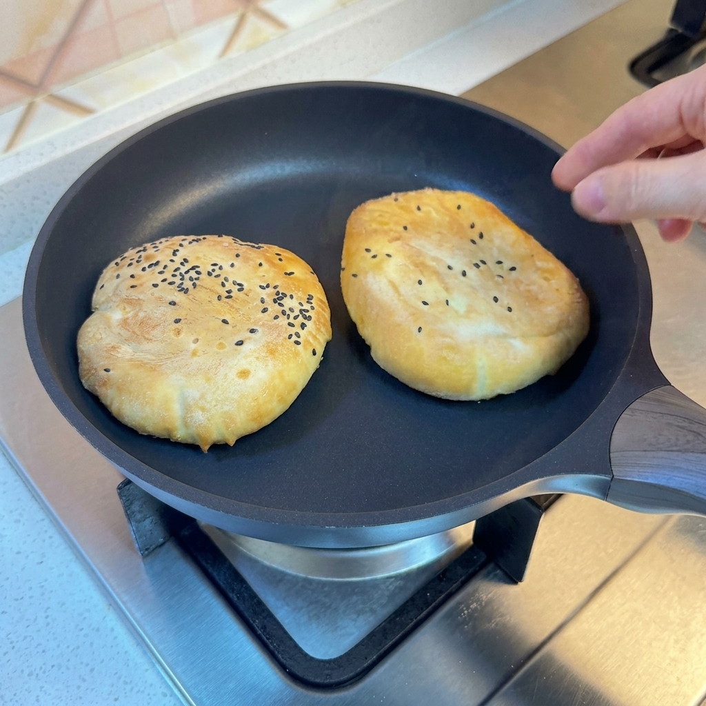 Buns in a pan covered with a lid, steaming.
