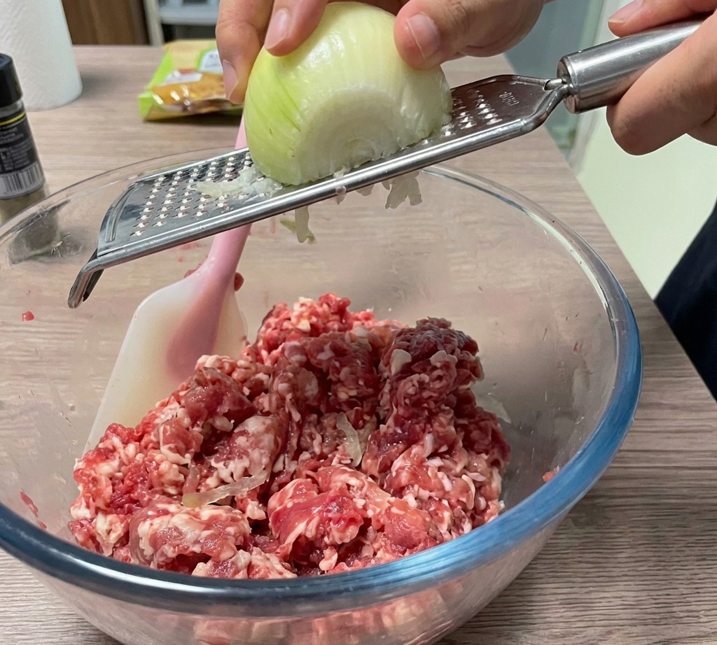 Onion being freshly grated into the bowl of meat.