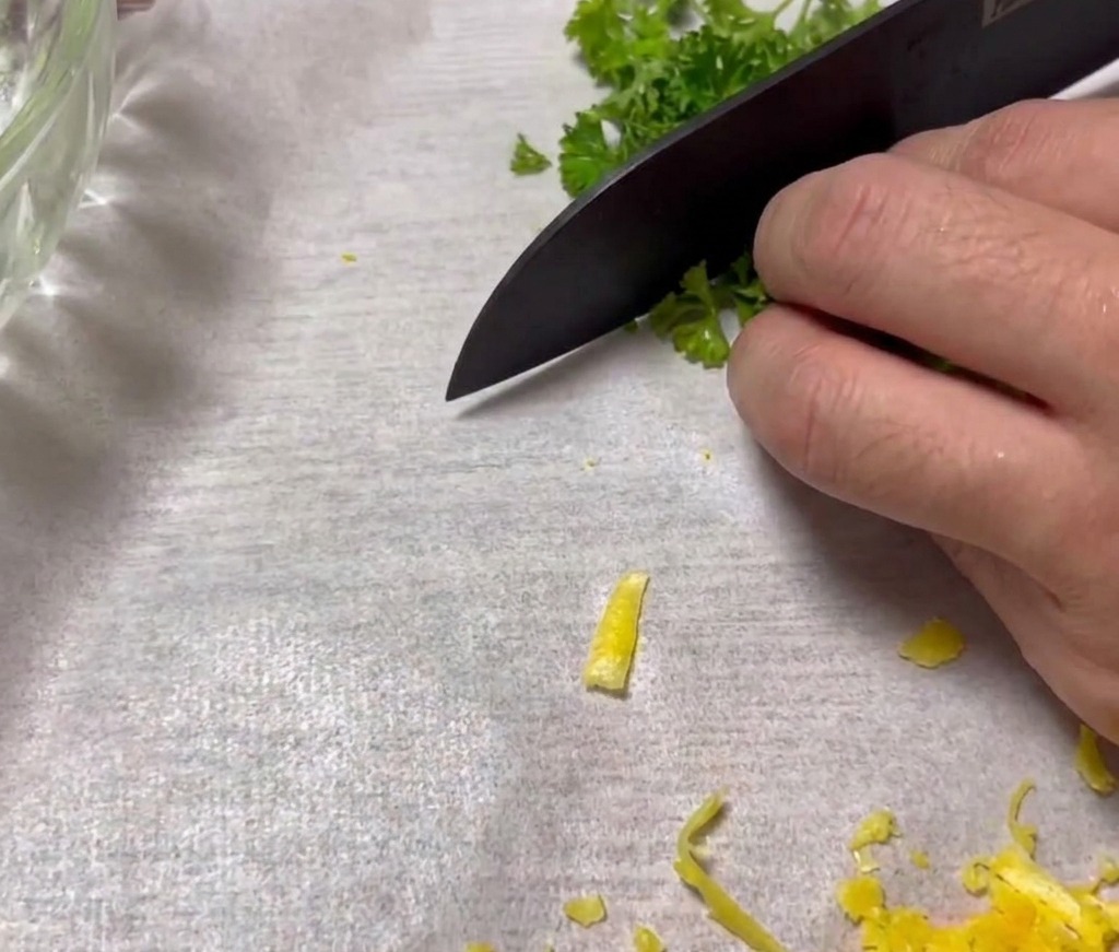 Finely chopped curly parsley on a cutting board, ready to be used as a garnish.