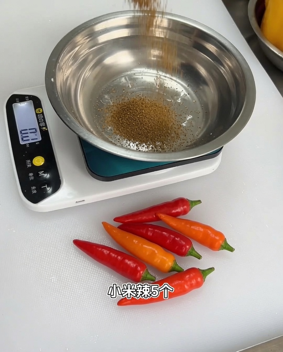A mix of aromatic spice powders being measured into a metal bowl on a digital kitchen scale.