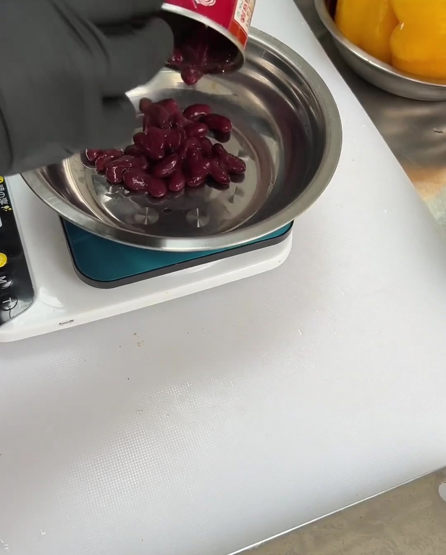 Red kidney beans being added to the bowl with spices and peppers.