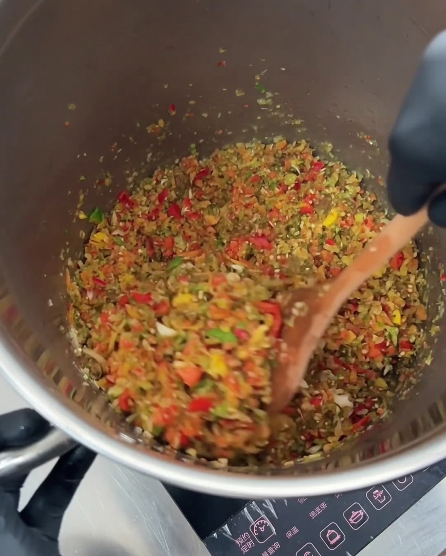 Red kidney beans and golden corn kernels being stirred into the sautéed vegetable mixture.