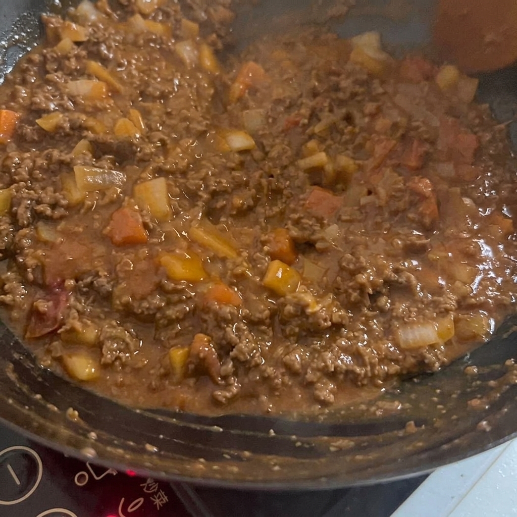 A rich, dark sauce being mixed into the beef and vegetable mixture in a hot wok.