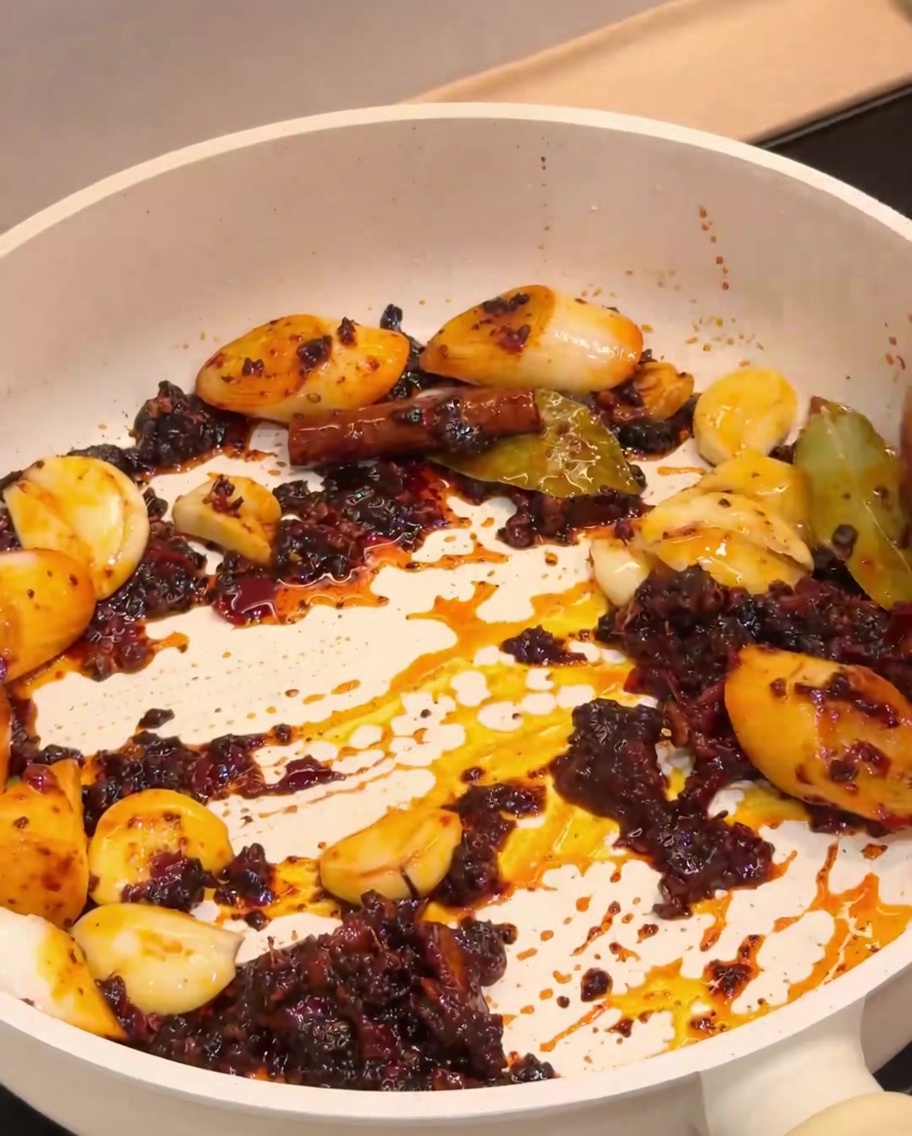 Fried crayfish being mixed with the aromatic spice base in a pan.