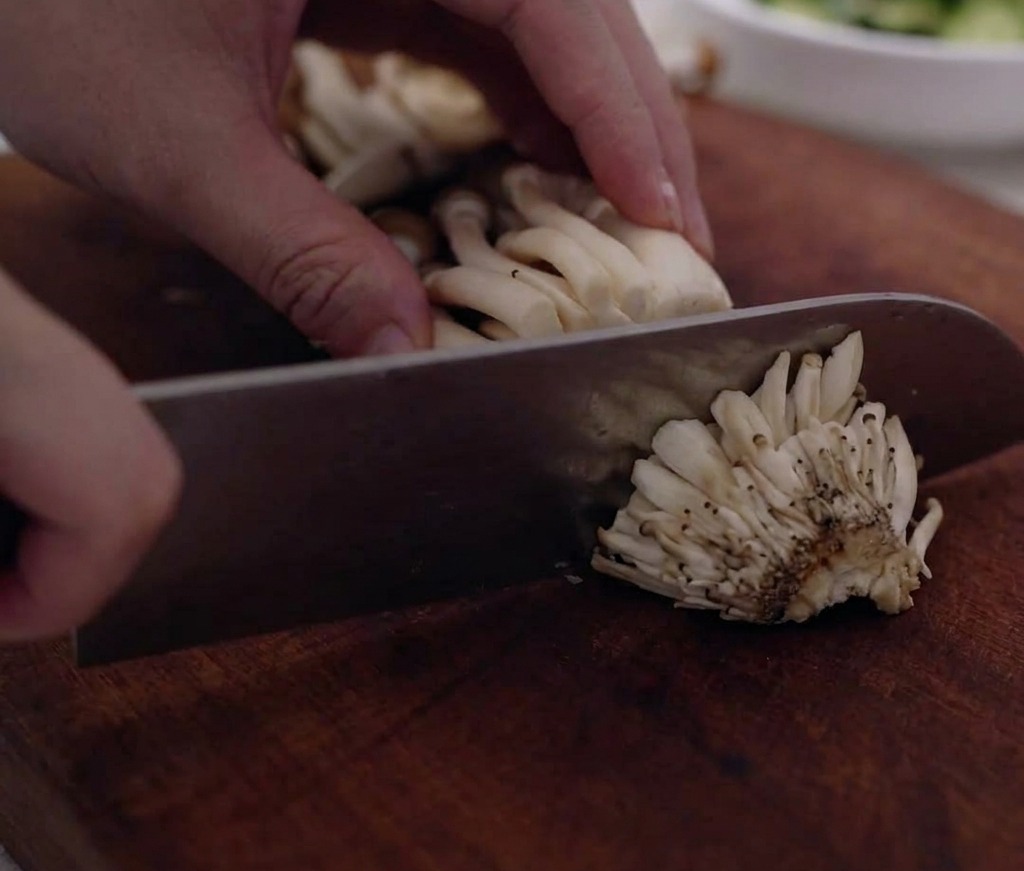 Shimeji mushroom clusters being trimmed and separated on a cutting board.