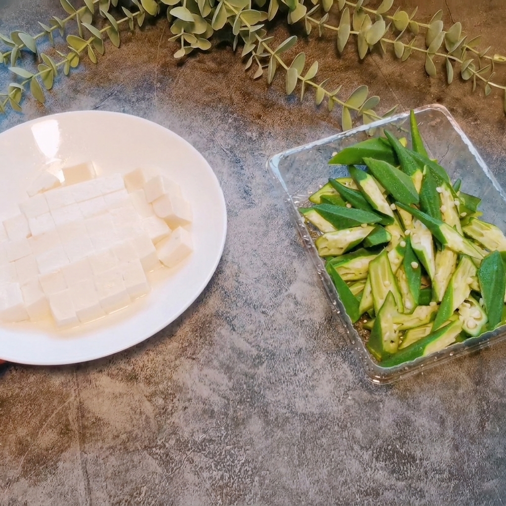 A block of soft tofu being cut into small, even cubes on a white plate.