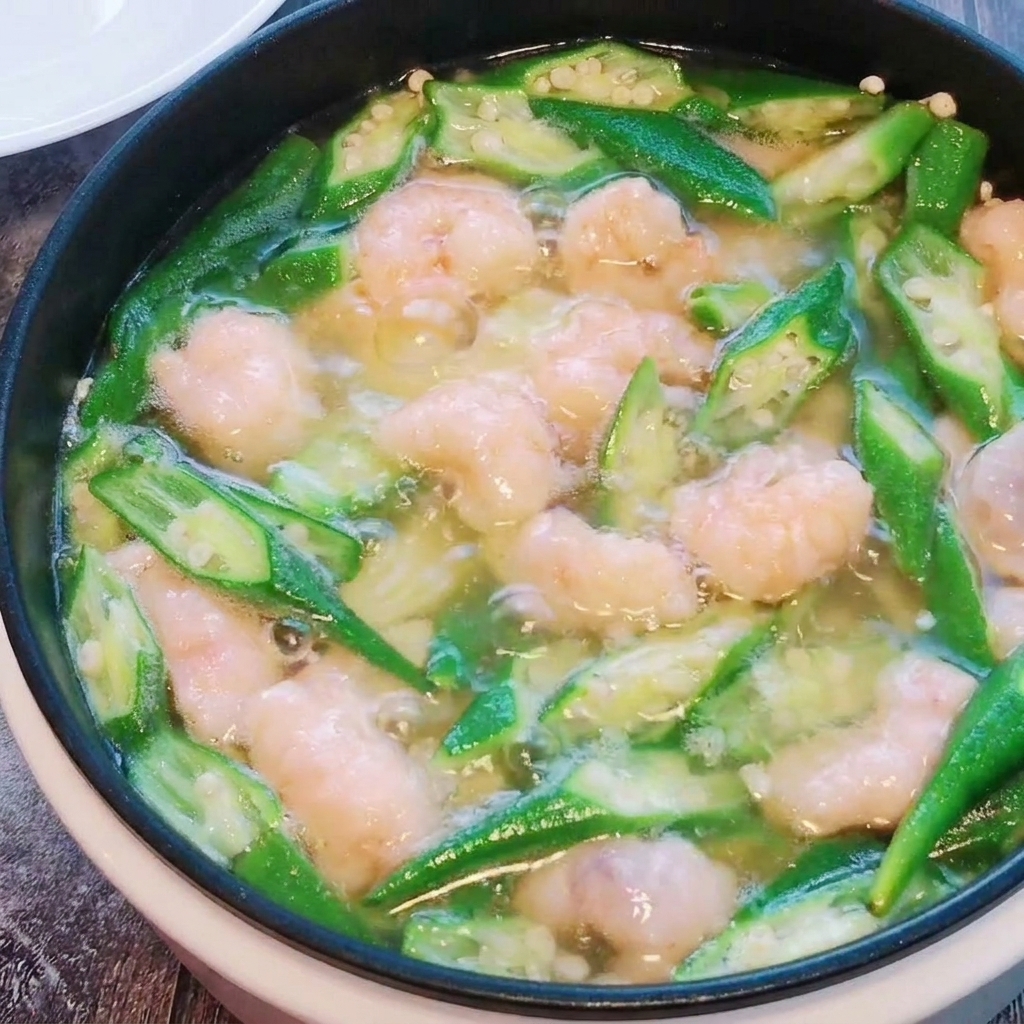The shrimp paste balls are being gently stirred into the okra and tofu soup as they cook.