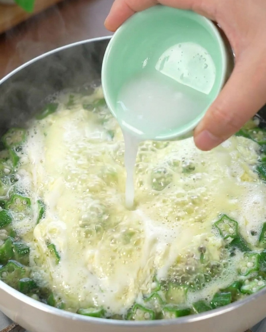 Starch water being poured into the bubbling Okra Egg Drop Soup, thickening the broth.