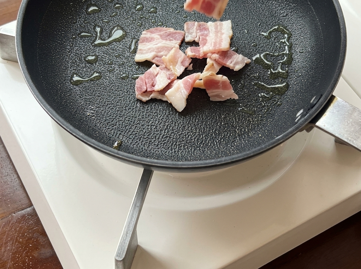 Sizzling bacon strips frying in a pan until golden brown and crispy.