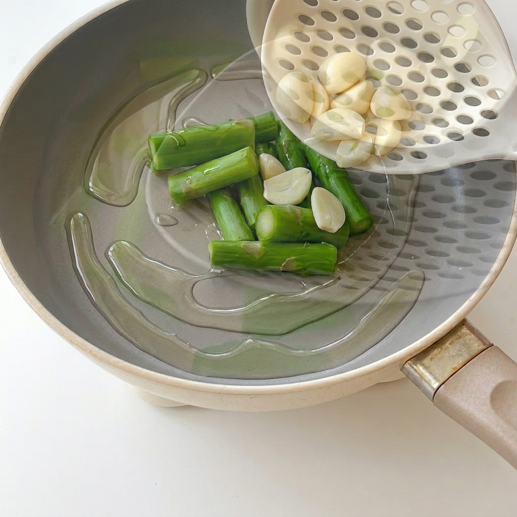 Garlic halves sautéing in a pan with hot oil.