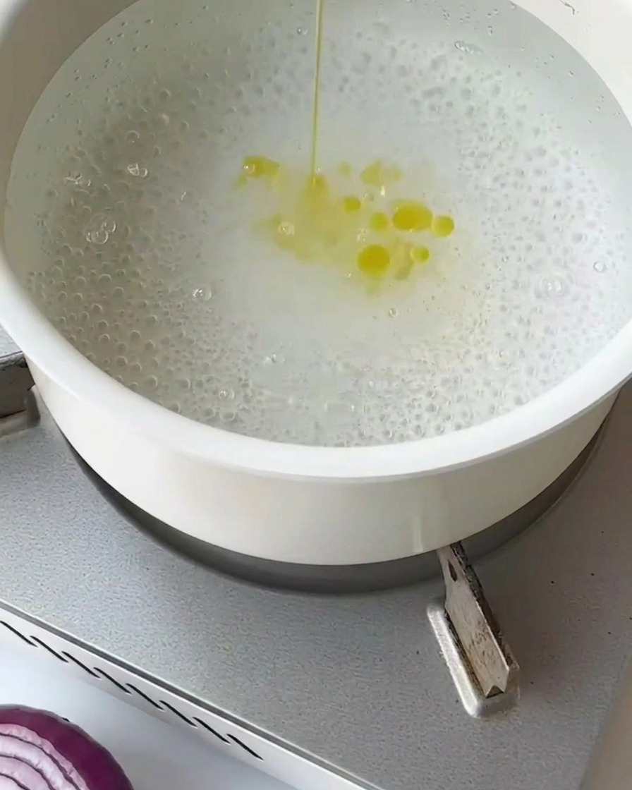 Asparagus segments being blanched in boiling water inside a wire mesh strainer.
