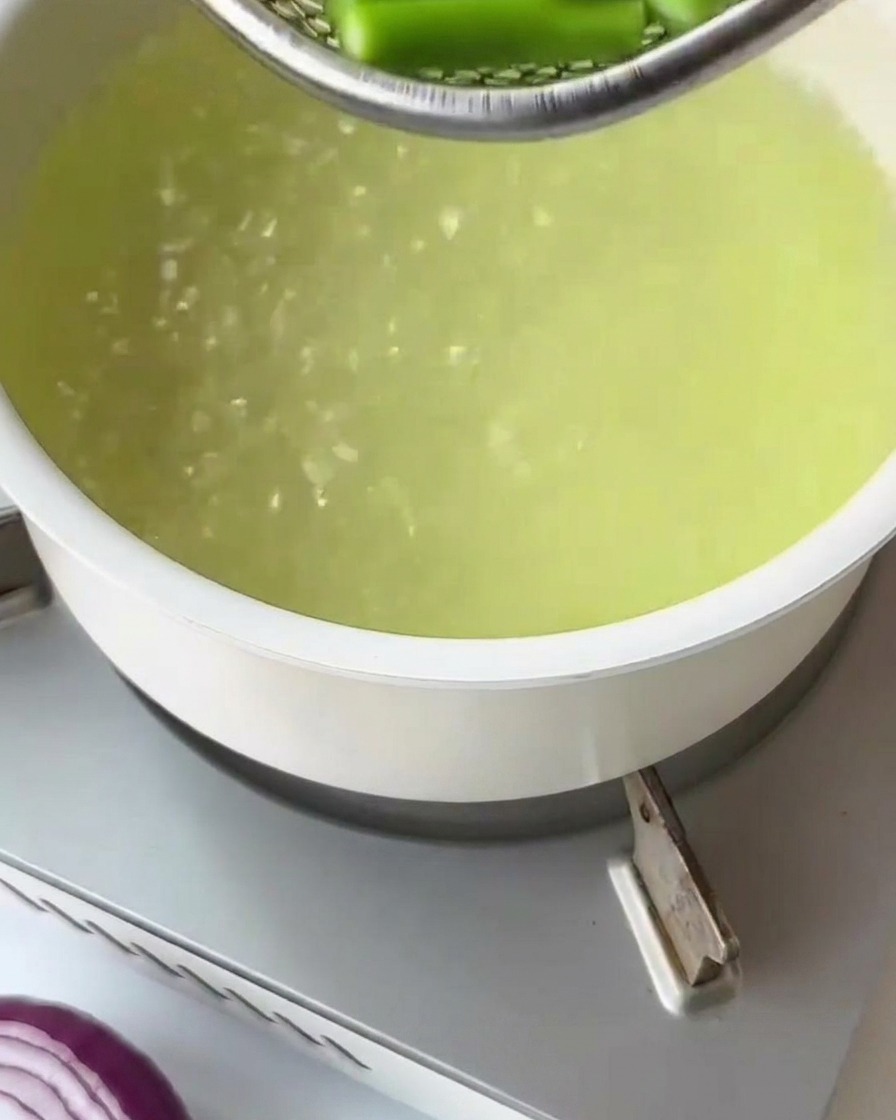 Dry fusilli pasta being dropped into a pot of boiling water.