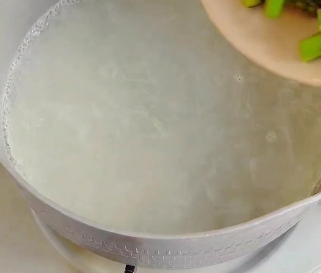 Asparagus segments being added to boiling water.