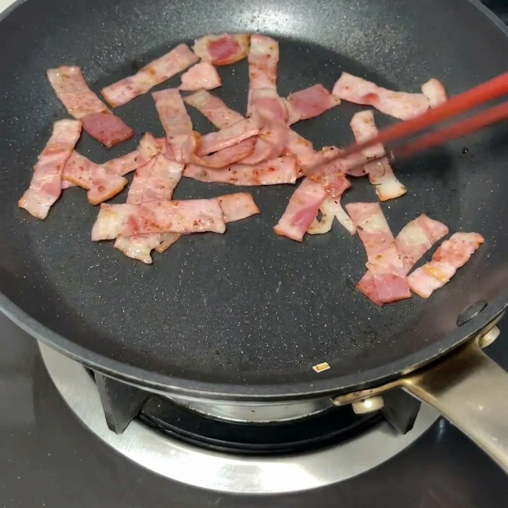 A golden knob of butter melting into the pan with browned bacon pieces.