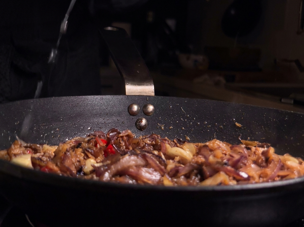 Fresh lemon juice being squeezed into the pan containing anchovies and aromatics.