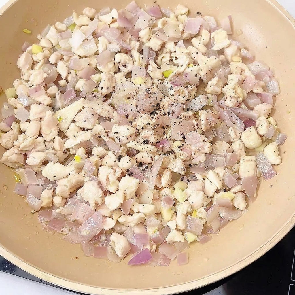 Chicken stir-fry in a pan being seasoned with various spices and sauces.