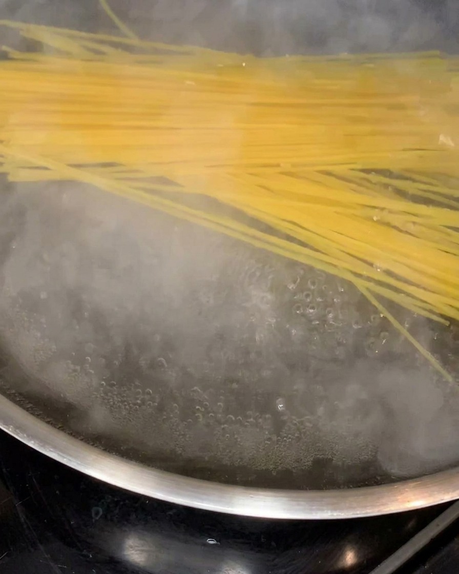 Spaghetti noodles softening and cooking in a large pot of rolling boiling water.