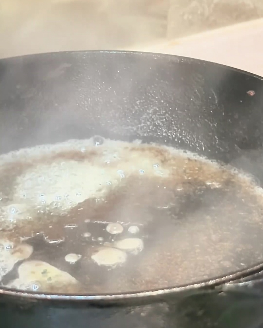 Liquid boiling rapidly in a hot skillet, releasing steam to deglaze the pan.