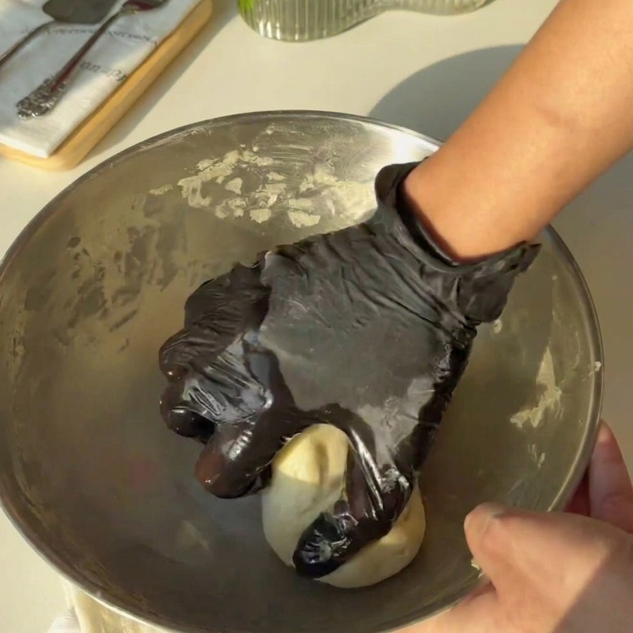 Smooth dough being kneaded by hand in a metal mixing bowl.