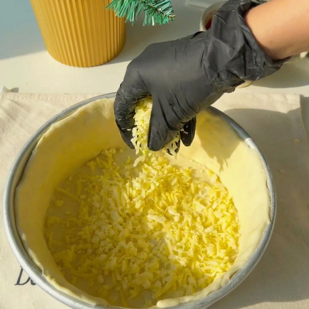 Shredded cheese being spread evenly over the base of the dough crust.