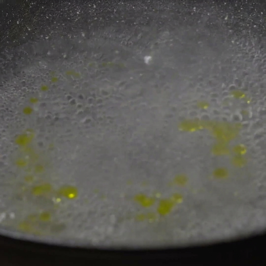 Dried paccheri pasta noodles being added into a pot of bubbling boiling water.