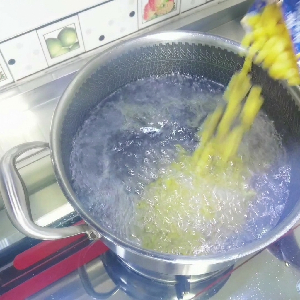 Dry yellow macaroni pasta being poured from a bag into a stainless steel pot of vigorously boiling water.