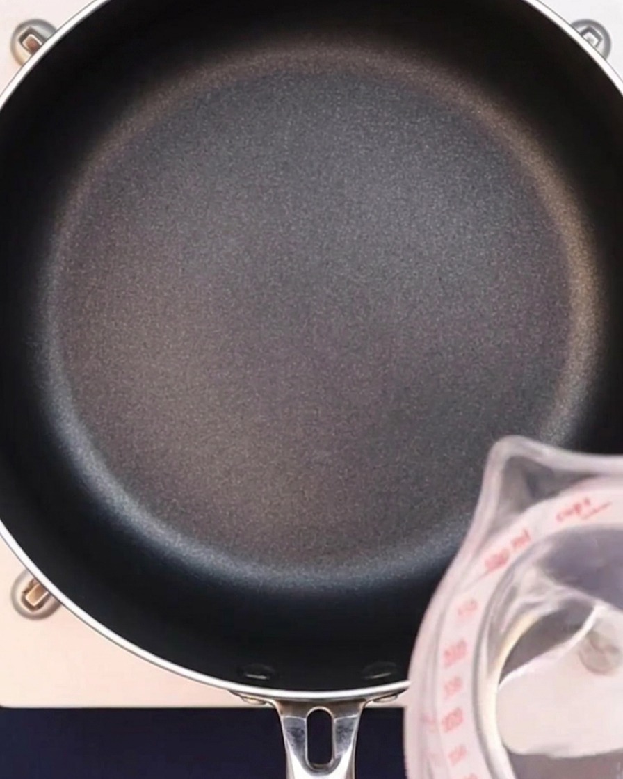 Water being poured into a black pan to start the curry broth.