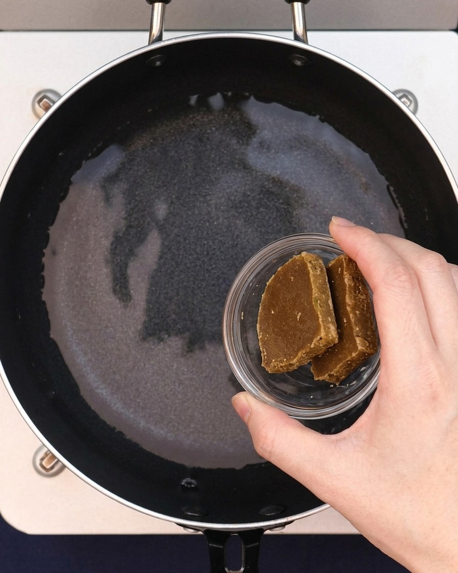 Two blocks of curry roux being added to the water in the pan.
